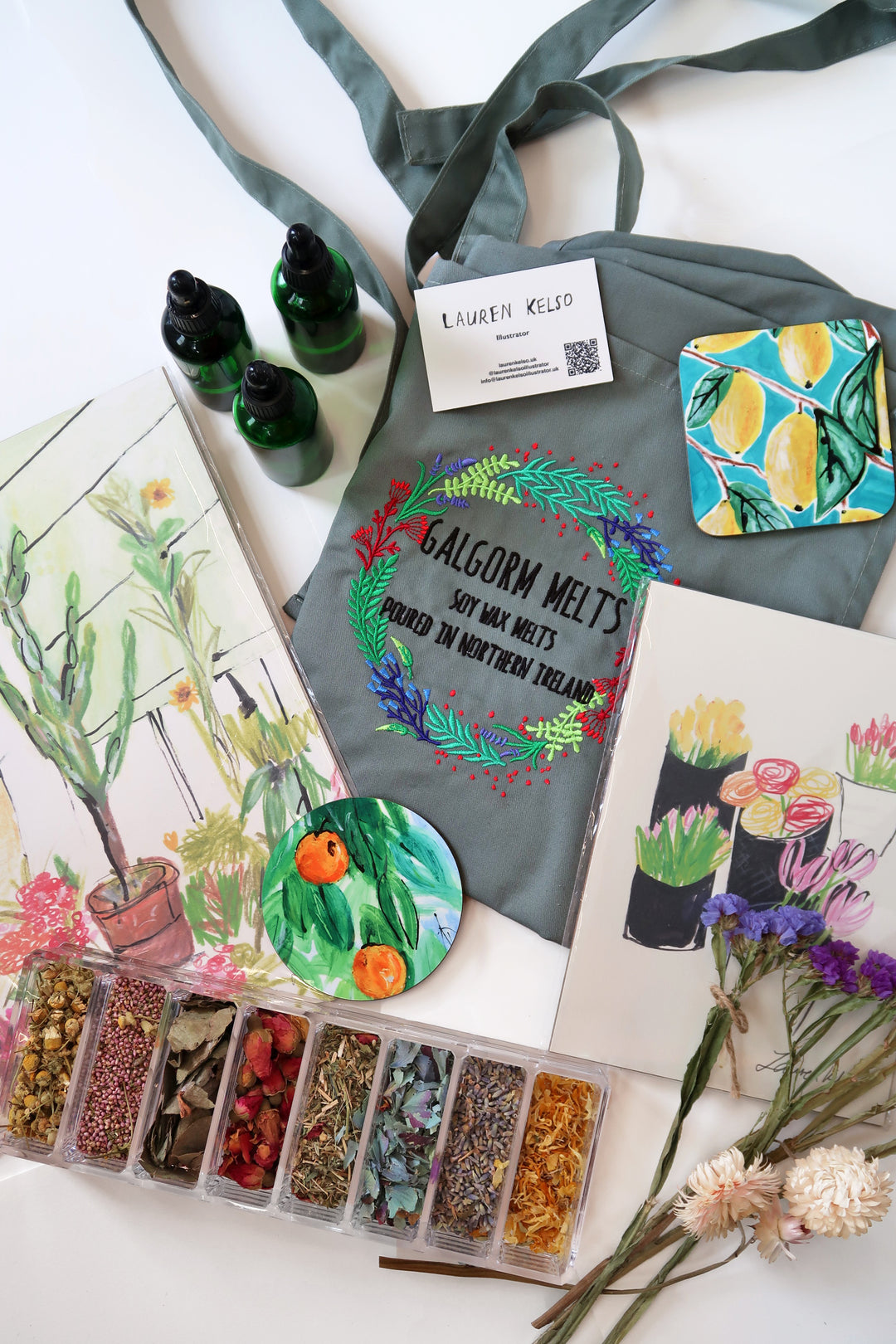 A styled flat-lay of a gray fabric tote bag with green handles, printed with the words &