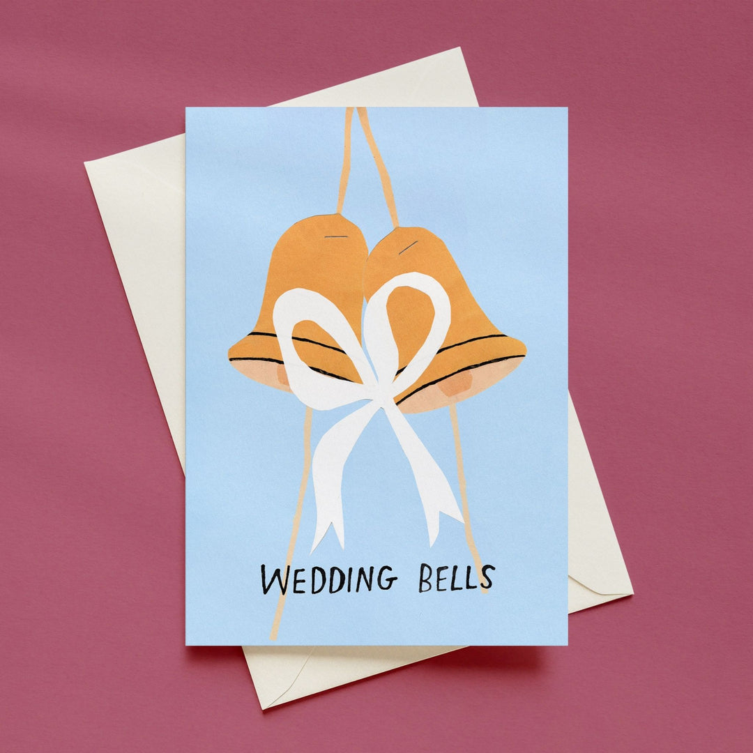 A square greeting card with an illustration of two gold wedding bells tied with a white bow on a light blue background, with the words &